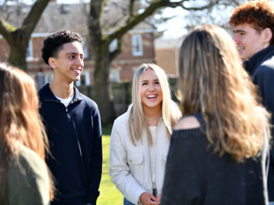 students standing in a group and laughing at the front of the College