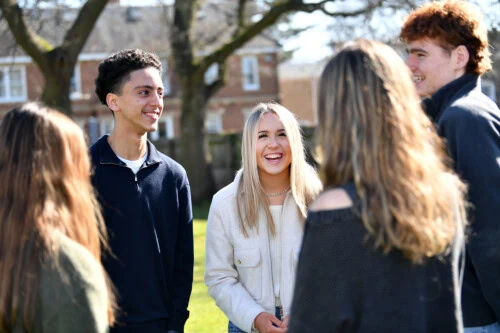students standing in a group and laughing at the front of the College