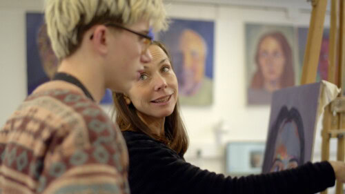 art teacher at a painting easel with a makle student