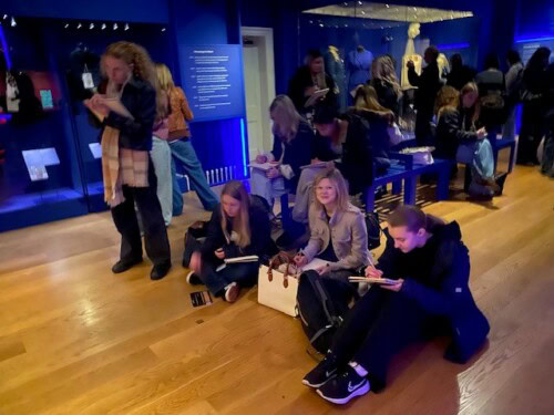 a group of students sitting in museum at sketching