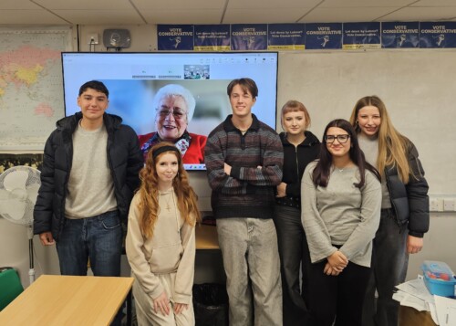 students standing in front of a screen featuring Baroness Harris Of Richmond