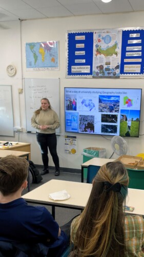 Geography alumni student presents to a classroom