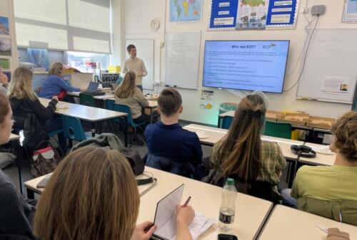 Guest speaker stand infront a classroom talking to Geography students