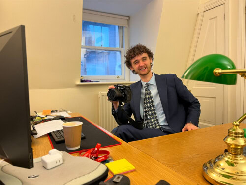 Joe at his desk holding a camera