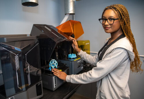 Girl stands at a 3D printer