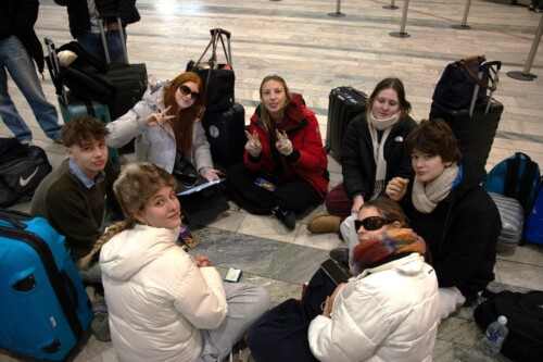 Group of students sitting on a floor of an airport