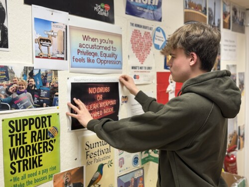 A politics student pinning a poster on the wall