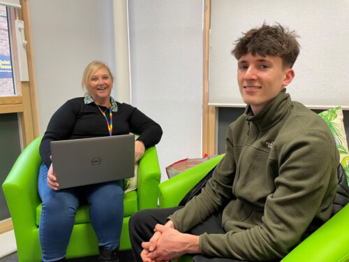 student sits in green chairs with a careers advisor