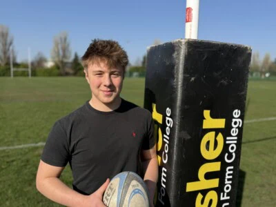 Student holding a rugby ball on rugby pitch
