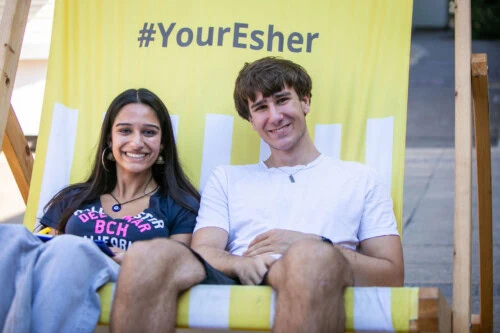 a boy and a girl sit together on a giant yellow deckchair