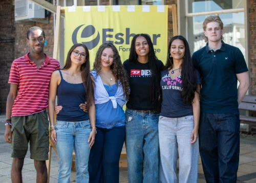 Group of outgoing SU stand infront of a giant yellow deck chair on resukts day smiling