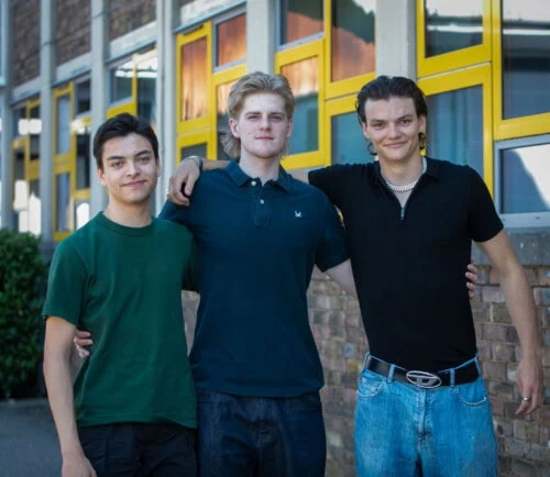 three male students stand should to should in dark coloured T shirts