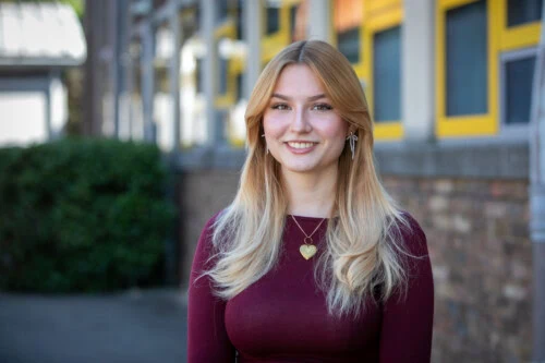 Girl with long blonde hair wears a red top