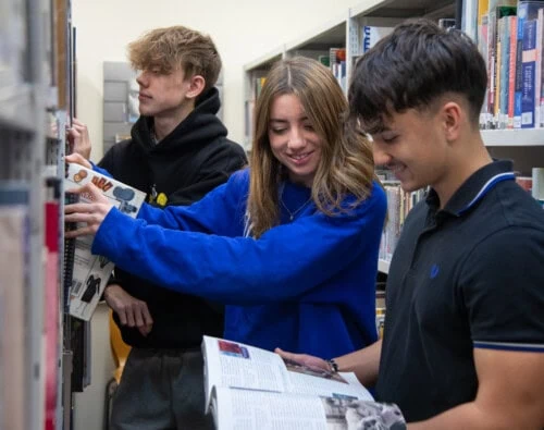 3 students in the library looking at books