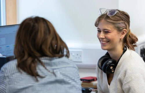 two students smiling at a computer in the ALN centre